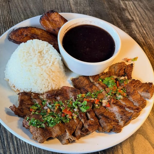 Grilled steak with chimichurri, white rice, fried plantains, and a side of black beans.
